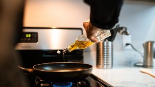 crop faceless chef pouring oil in pan